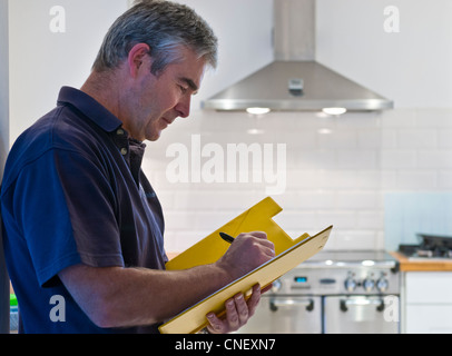 Enquête entretien Maison de propriété / évaluation ventes design homme dans t-shirt devis, réparation, écriture dans la cuisine domestique contemporaine maison Banque D'Images