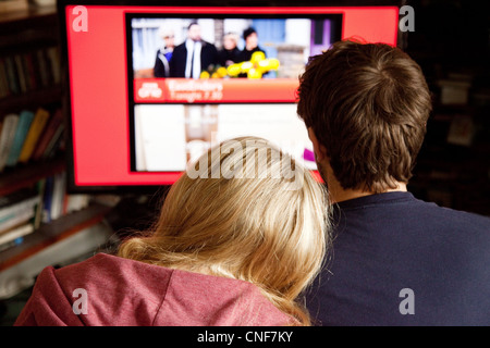 Vue arrière du jeune couple devant la télévision La télévision sur un grand écran, UK Banque D'Images