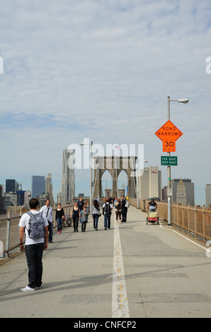 Les gens qui se balade Pont de Brooklyn pour piétons, vers la mi-span bridge tours et grattes-ciel de Manhattan, New York Banque D'Images