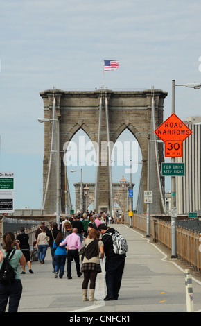 Portrait d'automne personnes marchant, young man, American flag flying haut de la tour, pont de Brooklyn, New York pour piétons Banque D'Images