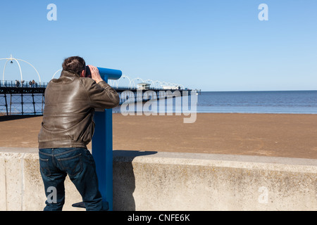 Seul homme de race blanche à télescope avec en mer et de la jetée de Southport en Angleterre Banque D'Images
