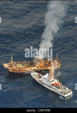 Le navire de pêche japonais Ryou-Un Maru brûlures après l'US Coast Guard Cutter Anacapa (droite) a tiré sur elle avec des munitions explosives, 5 avril 2012 dans le golfe d'Alaska. Le chalutier connu comme le navire fantôme circule à travers le Pacifique après avoir été jeté à la mer par le tremblement de terre de magnitude 9,0 a Banque D'Images