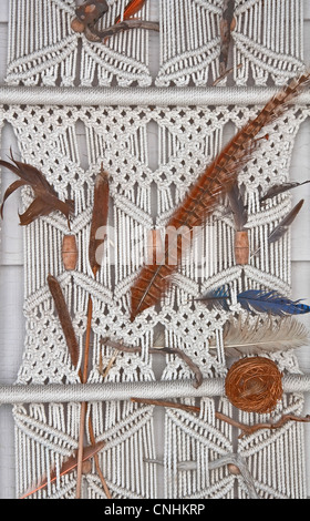 Partie d'un blanc avec des cordes faites de macramé dans un wall hanging, de plumes et d'autres éléments naturels ajoutés pour compléter. Banque D'Images