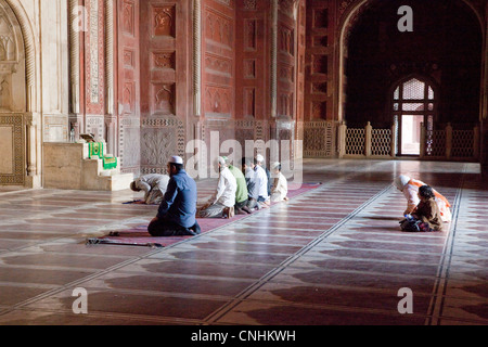 Agra, Inde. Mosquée du Taj Mahal. Fidèles à la mi-journée de prière. Remarque Femme et petite fille en arrière. Banque D'Images