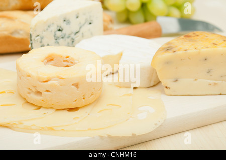 Différents types de fromage et raisins sur planche à découper en bois Banque D'Images