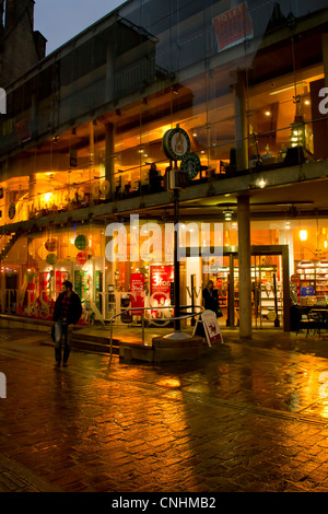 Lumière orange chaud de Waterstones et Starbucks dans Bradford Wool Exchange, réfléchissant sur pavés au crépuscule. Banque D'Images