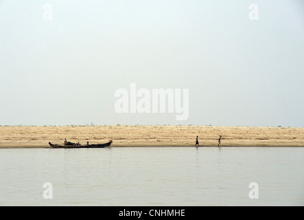 Deux enfants birmans en tirant un bateau le long de la berge. La rivière Irrawaddy, Bagan Birmanie. Ayerwaddy, Myanmar Banque D'Images