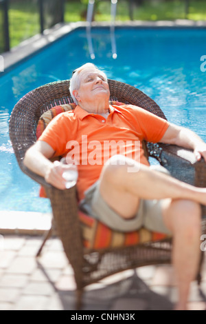 Un cadre supérieur retraité homme détente au soleil à côté d'une piscine Banque D'Images