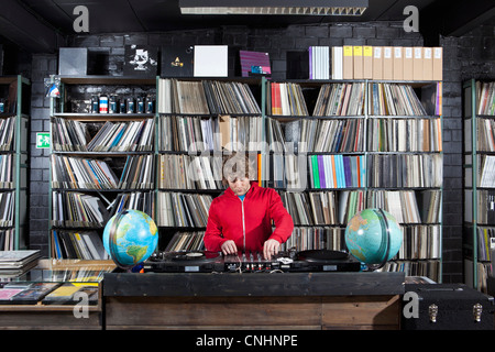 Un jeune homme à l'aide d'une table de mixage et platines DJ chez un disquaire Banque D'Images