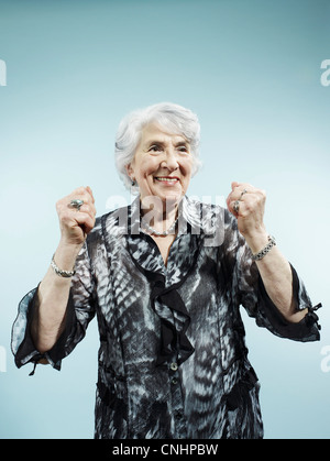 A senior woman with her arms raised in celebration Banque D'Images
