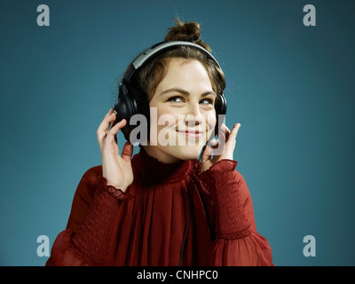 Une jeune femme portant des écouteurs et de la hanche smiling Banque D'Images
