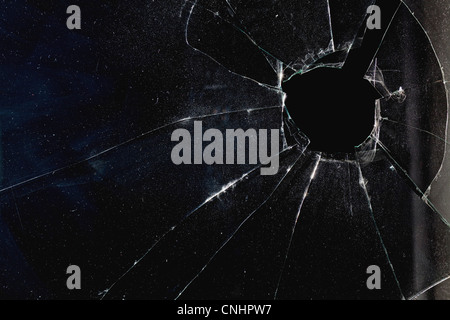 Une fenêtre avec un trou à travers le verre brisé, nuit Banque D'Images