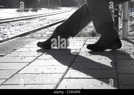 Le noir et blanc des images de silhouette d'une personne assise à l'attente d'une gare. Banque D'Images