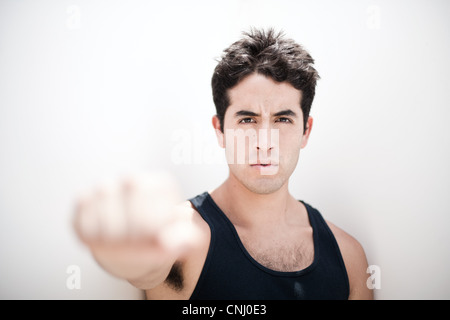 Young man holding fist out vers la caméra, se concentrer sur l'arrière-plan Banque D'Images