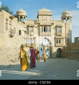 L'équilibrage des femmes sur leurs têtes des pots portant de l'eau de Gadisar Lake Inde Rajasthan Jaisalmer Banque D'Images