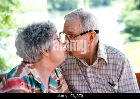 Un vieux couple américain pucker up pour un baiser pour célébrer leur 50e anniversaire de mariage sur une journée ensoleillée. Banque D'Images