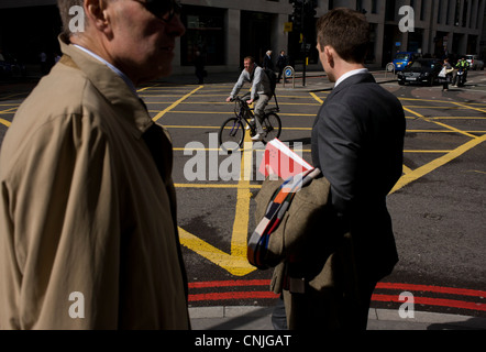 Les piétons et cyclistes qui se promène sur une case jaune junction grille dans une ville de London street. Banque D'Images