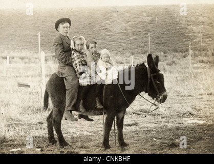 Quatre enfants équitation un âne noir Banque D'Images