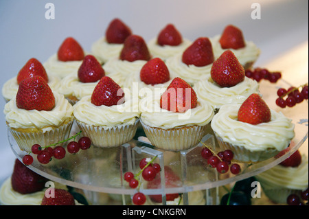 Cake stand avec des fraises fraîches et petits gâteaux de la crème ou du beurre avec givrage groseilles Banque D'Images