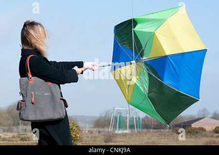 Femme mal à tenir son parapluie par grand vent Banque D'Images