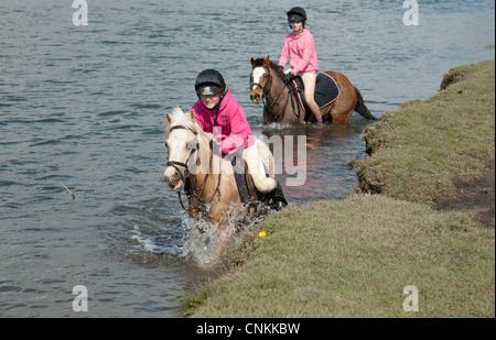 Pony riders traversant la rivière Ewenny Ogmore au dans la vallée de Glamorgan, Wales UK Banque D'Images