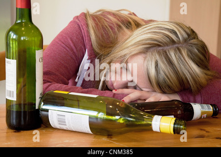 Jeune femme alcoolique ivre, avec des bouteilles vides d'alcool, UK - posée par un modèle Banque D'Images