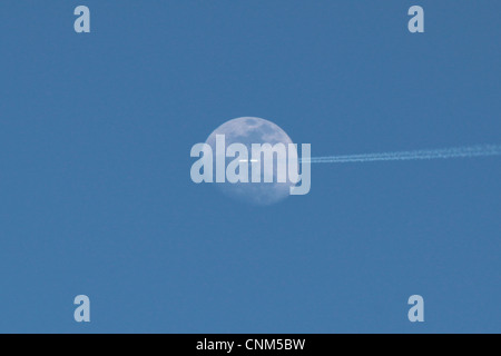 Avion dans le ciel contre la pleine lune pendant la journée Banque D'Images