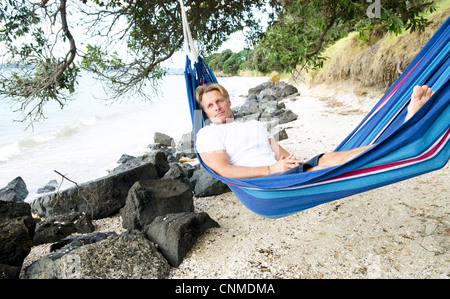 Un homme pensif pose dans un hamac sur la plage. Banque D'Images