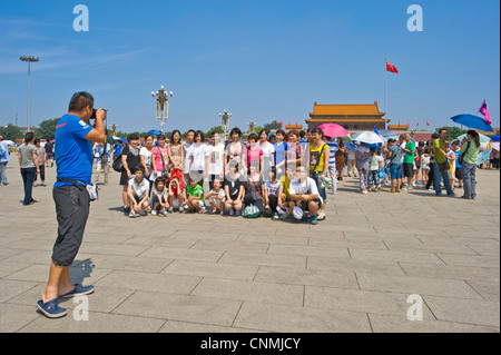 Un groupe de touristes chinois de la Place Tiananmen, avoir leur photo prise, la Cité Interdite est entrée dans l'arrière-plan. Banque D'Images