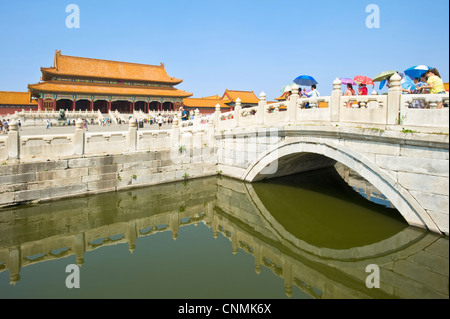 Touristes traversant l'un des ponts de la rivière d'or" à l'intérieur de la Cité Interdite avec la porte de l'harmonie suprême dans l'arrière-plan Banque D'Images