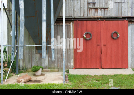 Portes de grange rouge et des guirlandes accroché sur eux sur une grange à côté d'un vieux grain bin Banque D'Images