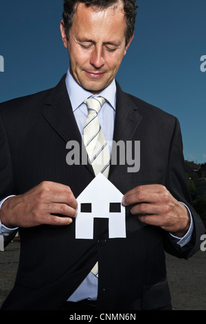 Businessman holding paper house Banque D'Images