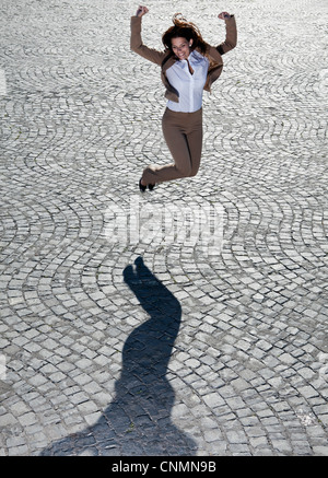 Businesswoman jumping sur route pavée Banque D'Images