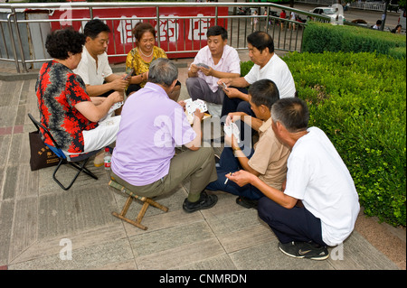 Un groupe de personnes vous détendre dans un parc/square cartes à jouer dans le centre de Chengde. Banque D'Images