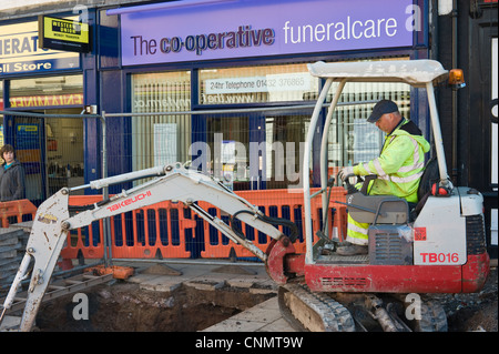 L'homme à l'extérieur du trou d'excavation mini digger CO-OPERATIVE FUNERALCARE en centre-ville de Hereford Herefordshire Angleterre UK Banque D'Images