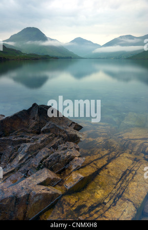 La photographie de portrait de la vue sur l'eau en direction de Great as Gable et Scafell sur l'apparence d'un jour brumeux. Banque D'Images