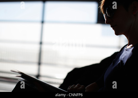 Woman Reading magazine in airport Banque D'Images