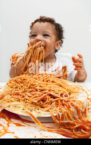 Boy eating Spaghetti aux mains Banque D'Images