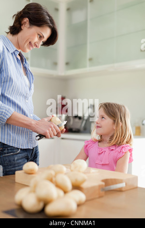 Mother helping daughter peler les pommes de terre Banque D'Images