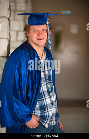 Homme high school student in graduation outfit sur campus de l'école Banque D'Images