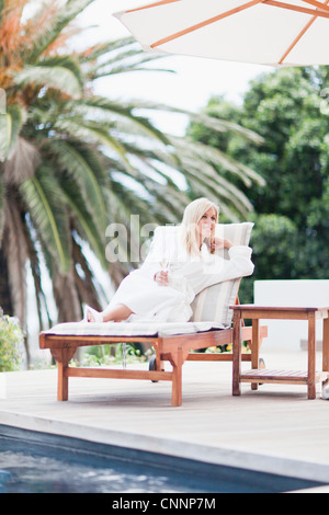 Woman in bathrobe relaxing by pool Banque D'Images