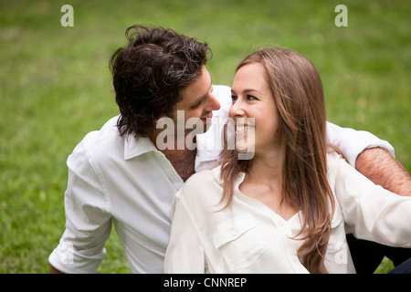 Close-up Portrait of Young Couple Sitting on Grass in Park Banque D'Images