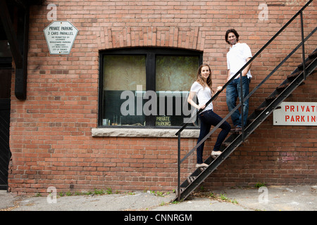 Portrait of Young Couple debout sur un escalier de secours de ruelle, Toronto, Ontario, Canada Banque D'Images