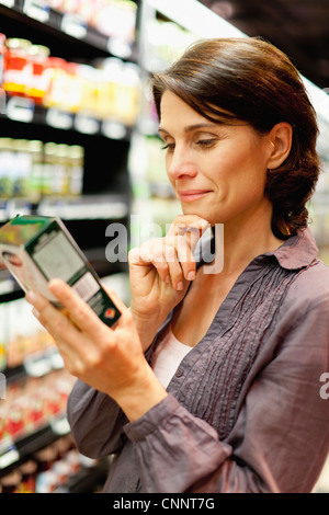 Femme lisant fort in grocery store Banque D'Images