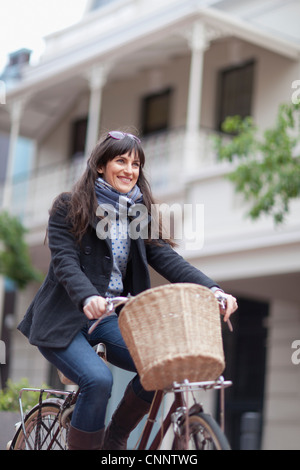 Woman riding bicycle on city street Banque D'Images