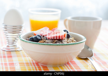 Bol de muesli avec des fraises et des bleuets, un œuf, le jus d'orange et café pour petit déjeuner sain Banque D'Images