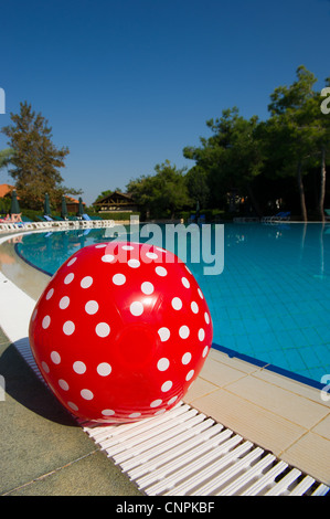 Ballon de plage en pointillés rouges portant près de la piscine extérieure Banque D'Images