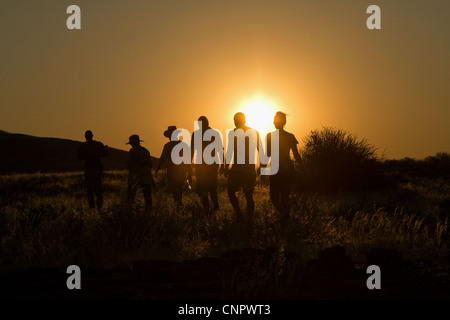 Trekking à travers la brousse africaine au coucher du soleil, la Namibie, l'Afrique Banque D'Images