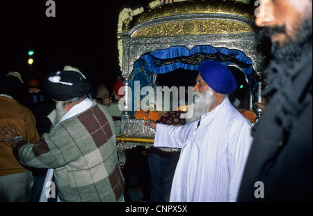 Les hommes sikhs portant Guru Granth Sahib (livre sacré des Sikhs) au Golden Temple à Amritsar, en Inde. Banque D'Images