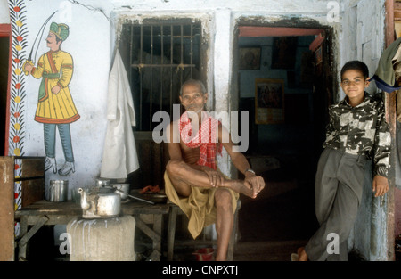L'homme Indien et le garçon à l'entrée de leur maison à l'ancienne ville indienne de Bénarès (Varanasi), de l'Uttar Pradesh, Inde. Banque D'Images